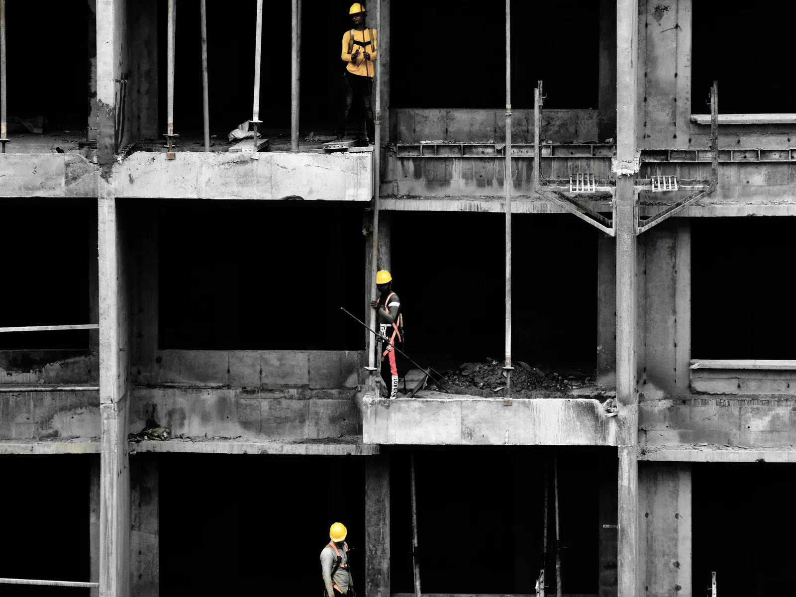 Workers standing on the open floors of a concrete frame under construction