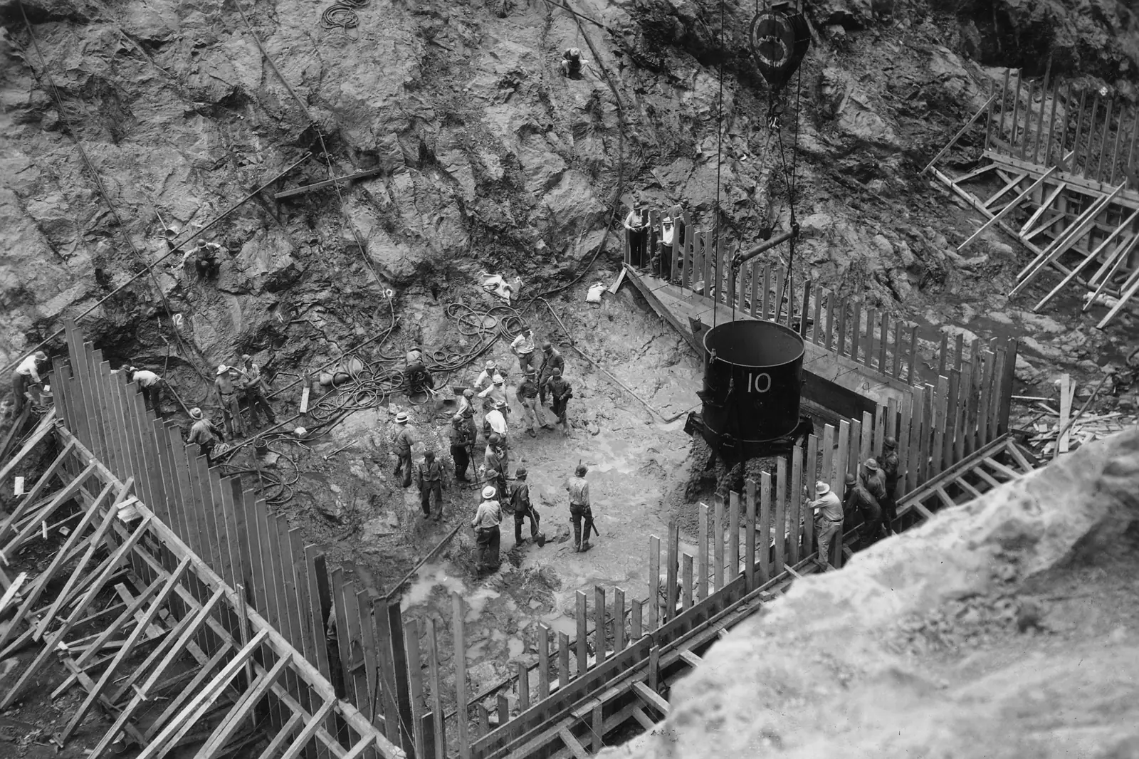 A crew in the foundation of Boulder Dam watching the first bucket of concrete being lowered